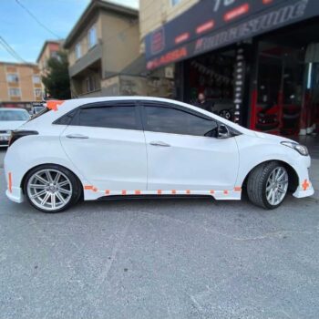 Yol kenarında park etmiş beyaz performans otomobili, modifiye ve yarış otomobili parçaları ile detaylandırılmış.